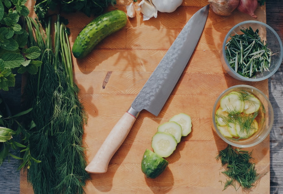 Μαχαίρι σεφ επάνω σε επιφάνεια κοπής με λαχανικά δίπλα